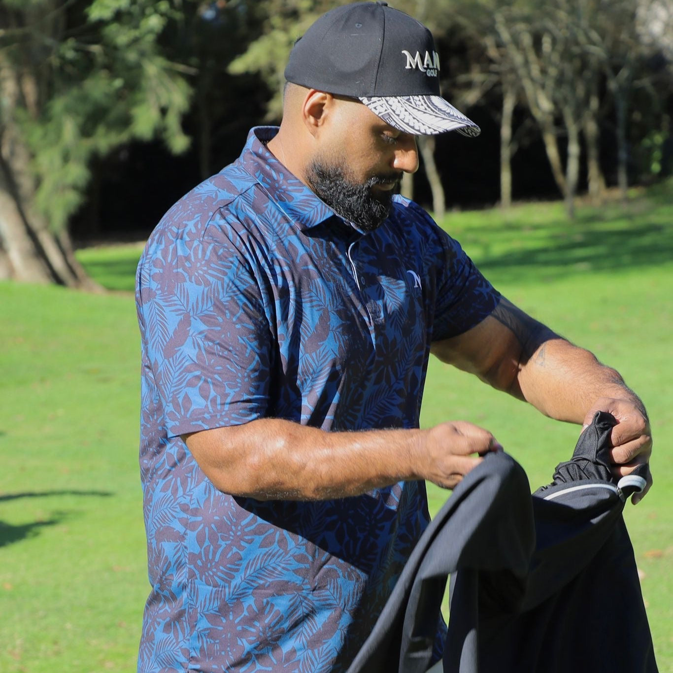Model in the Island Nights Polo shirt, black with subtle Polynesian patterns, designed for golfers. Proudly designed in New Zealand.