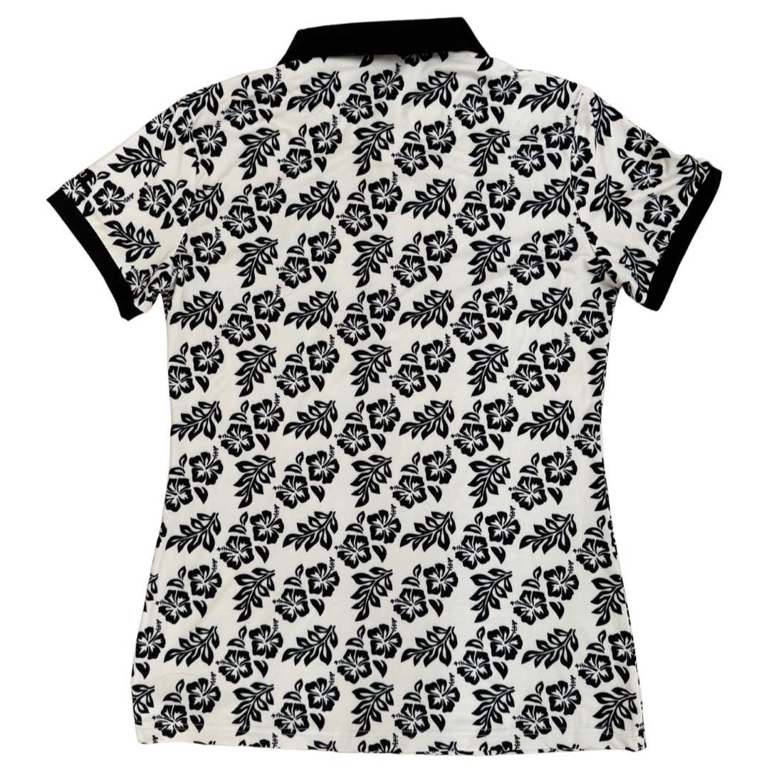 Back view of Island Grace Women’s Golf Polo in white with black frangipani floral pattern, ideal for golfers.