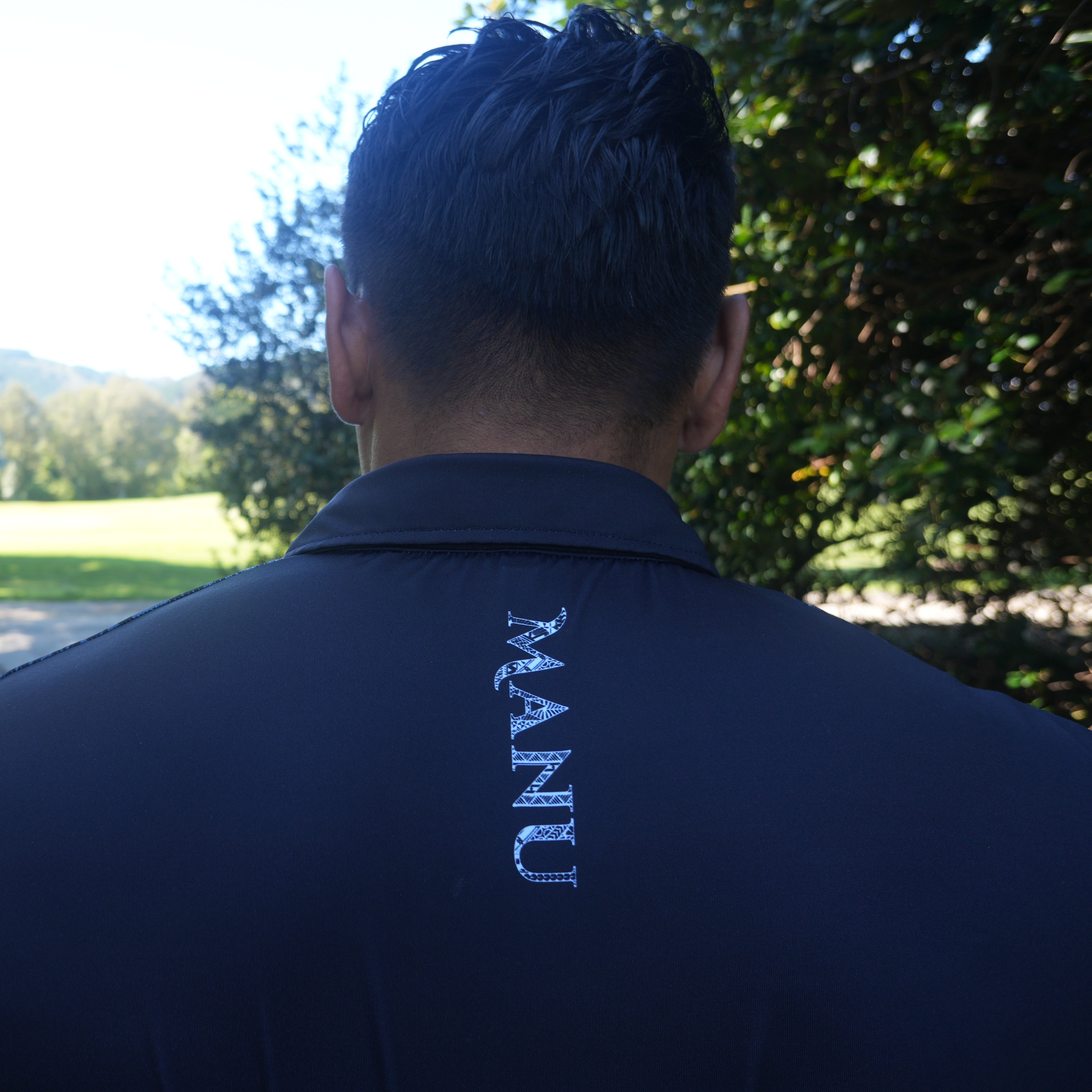 Back view of a man in a classic black golf polo featuring a stylish embroidered logo.