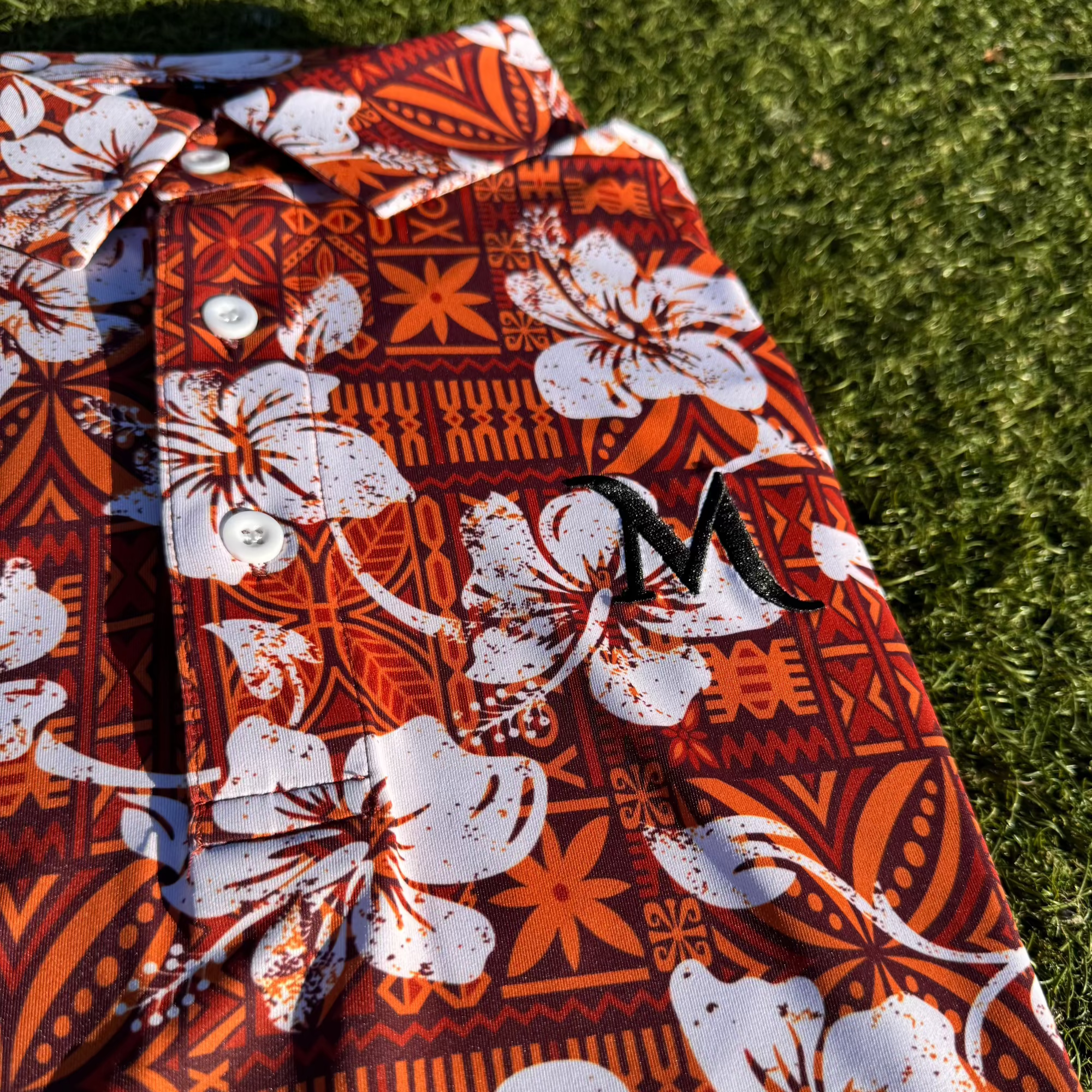 Close up of the island roots golf polo. Showing the island patterns and frangipani design. Mens golf polo inspired by Polynesian culture.