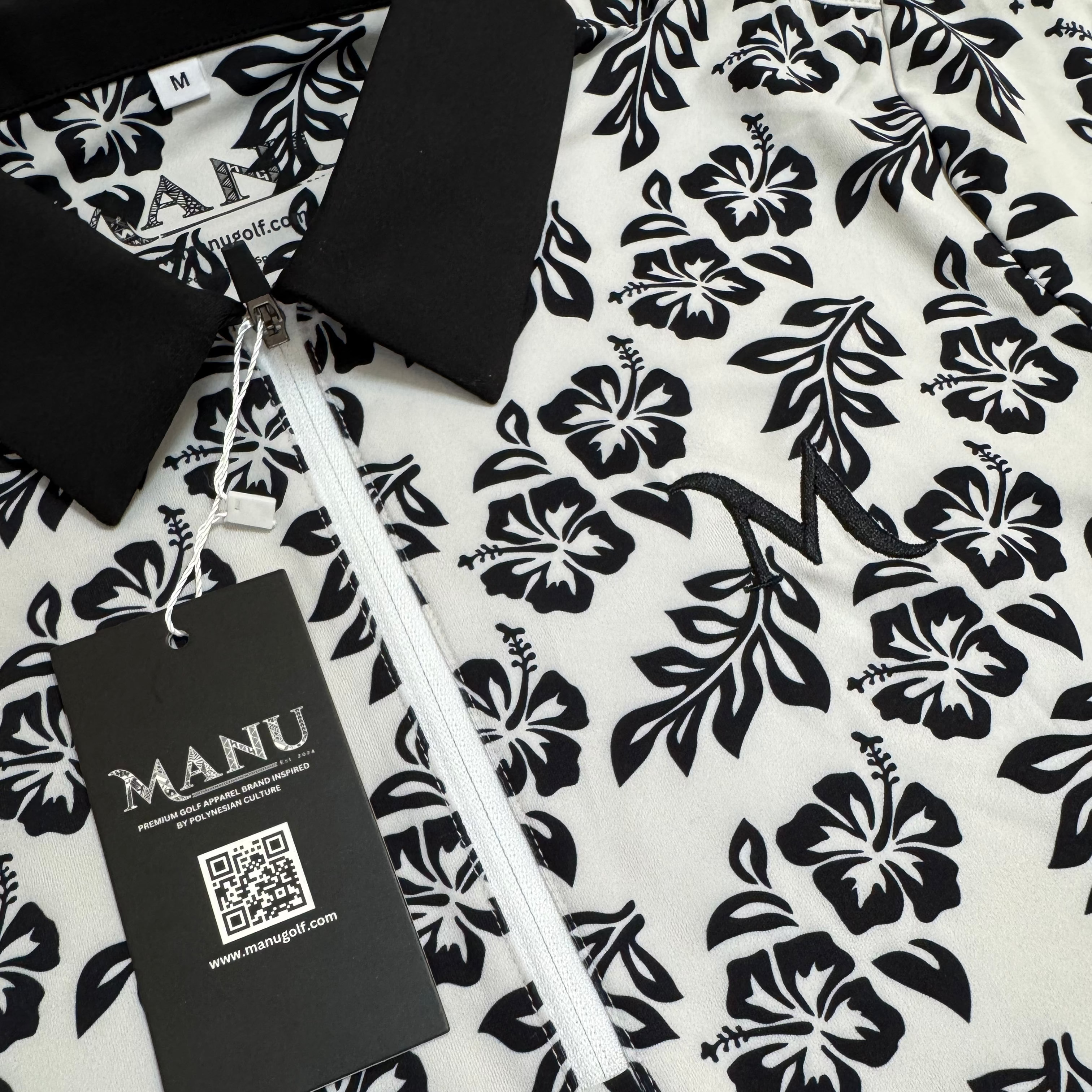 Close-up of Island Grace women’s polo showing black frangipani floral design