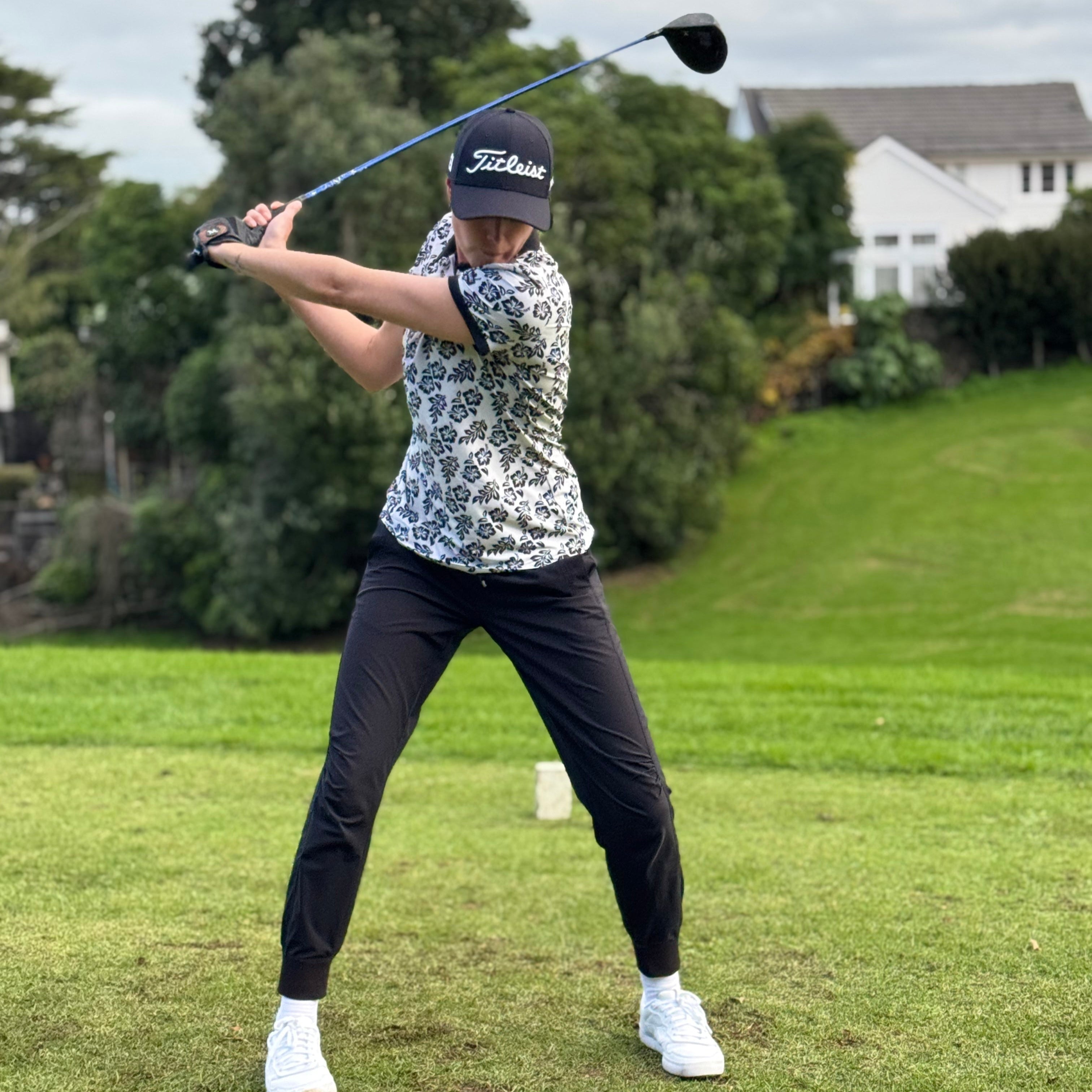 Model in the Island Grace Women’s Golf Polo – White with Black Frangipani featuring Polynesian-inspired patterns for a stylish golf look. Proudly designed in New Zealand.